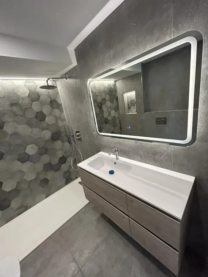 Baño con azulejo hexagonal gris y espejo con luz