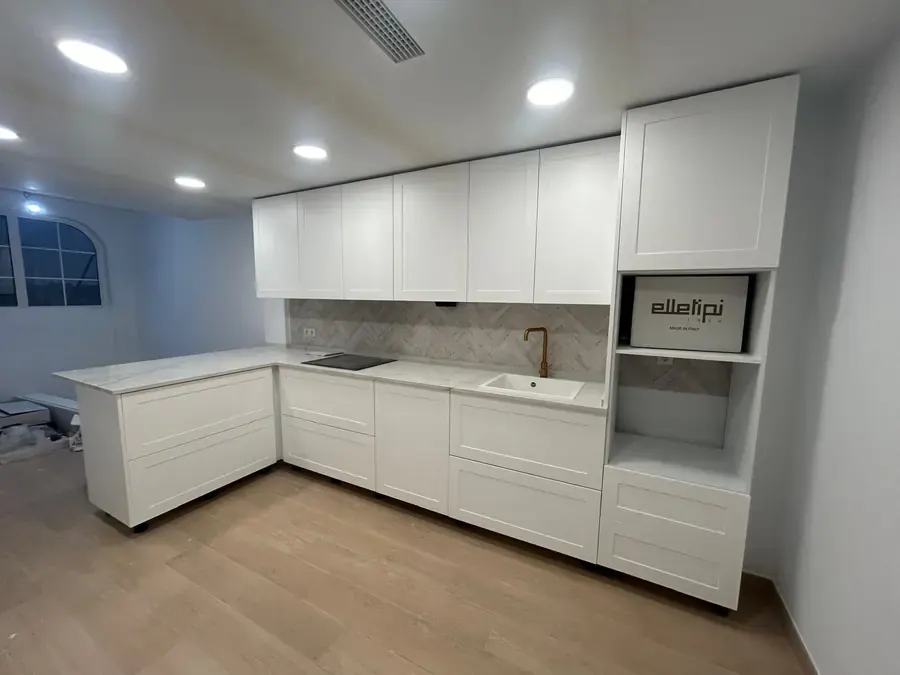 Cocina blanca en L con muebles altos hasta el techo