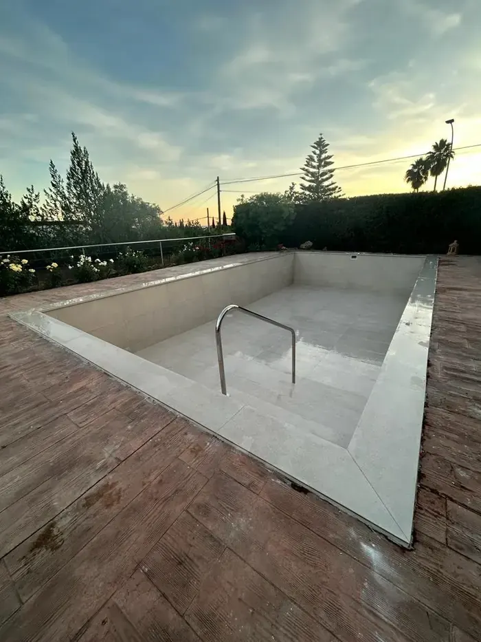 Piscina exterior con escalera de acero al atardecer