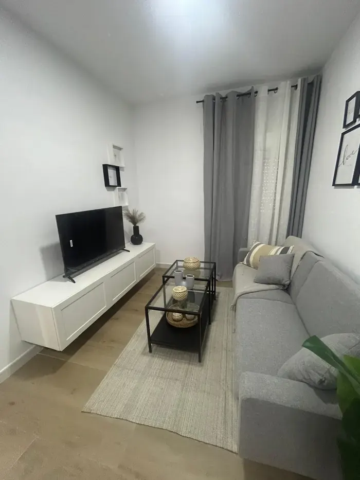 Salón con mueble de televisión blanco y alfombra clara