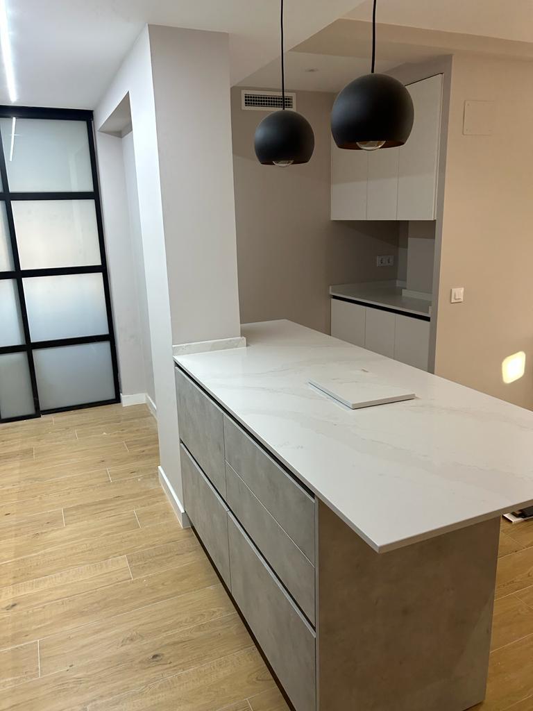 Cocina reformada minimalista moderna, suelo imitacion madera, isla central.